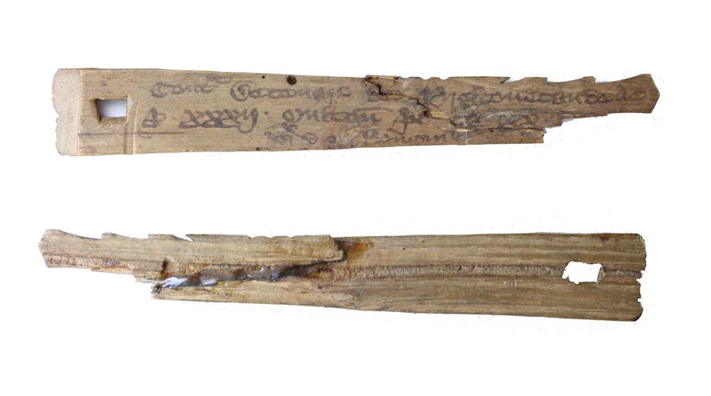 Two halves of a medieval split hazel tally stick with notches and writing
